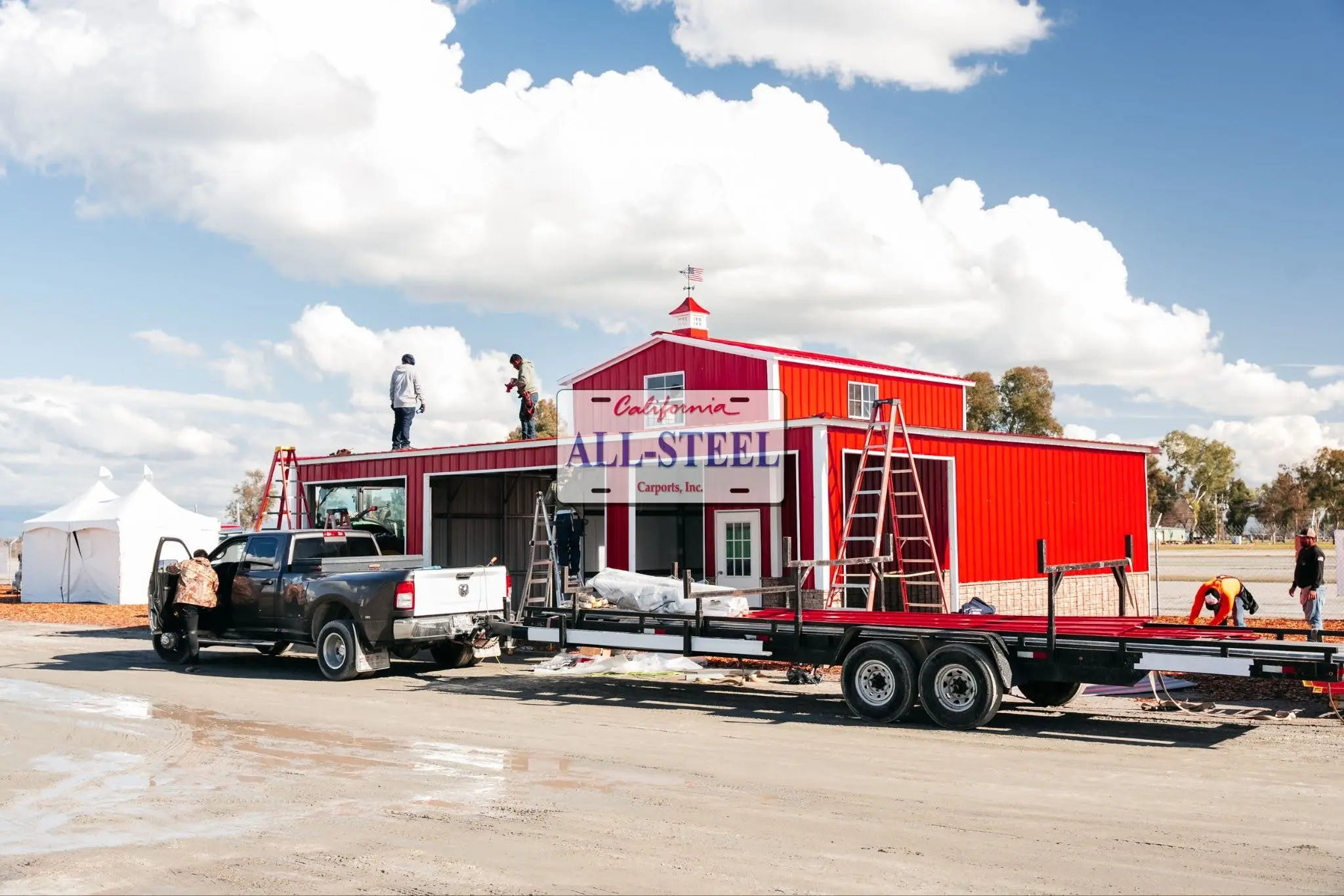 Crew installing roof panels on a red barn steel building
