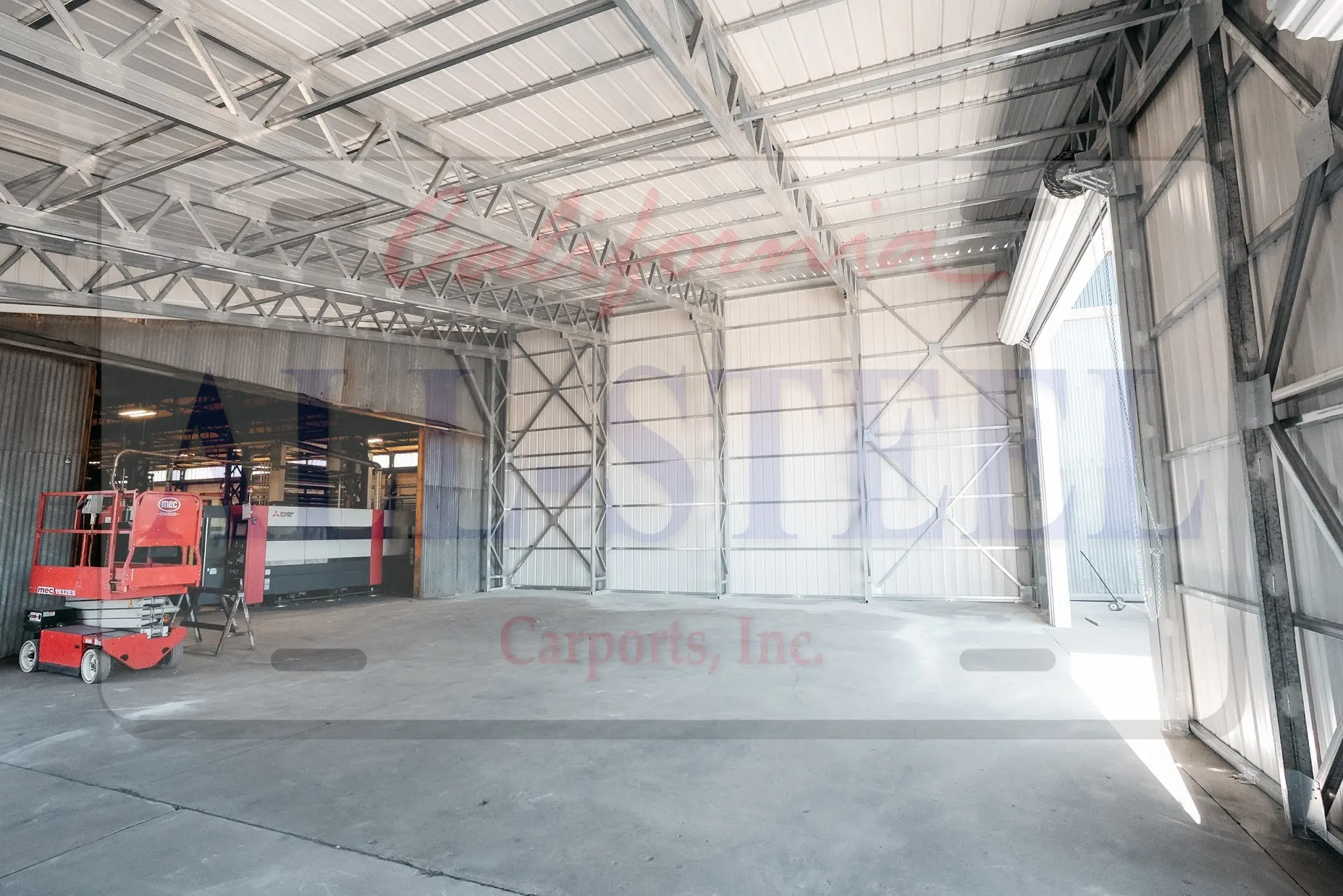 Exposed steel framing and a wide roll-up doorway inside a metal building