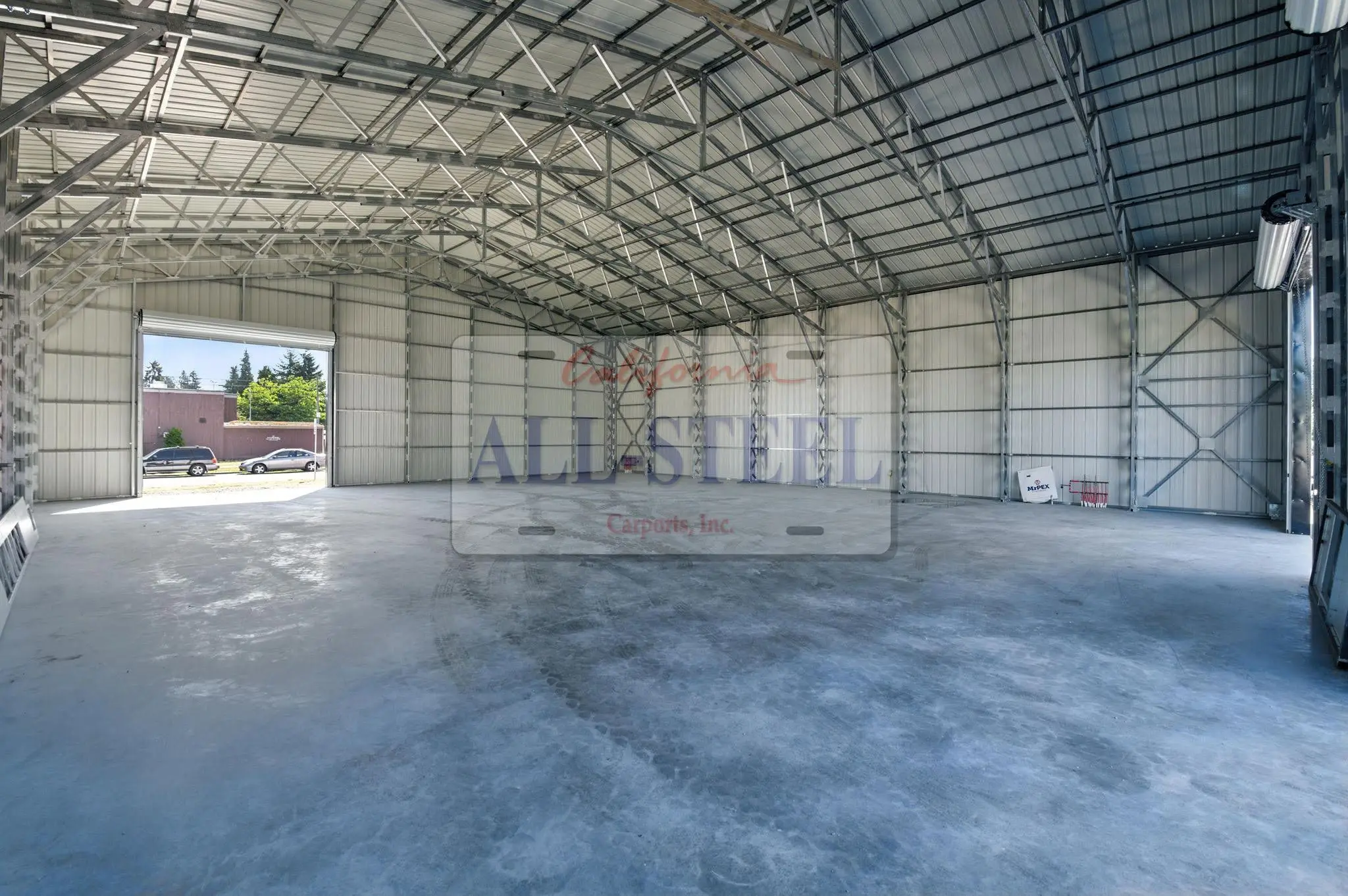 Exposed steel framing and a wide roll-up doorway inside a metal building.