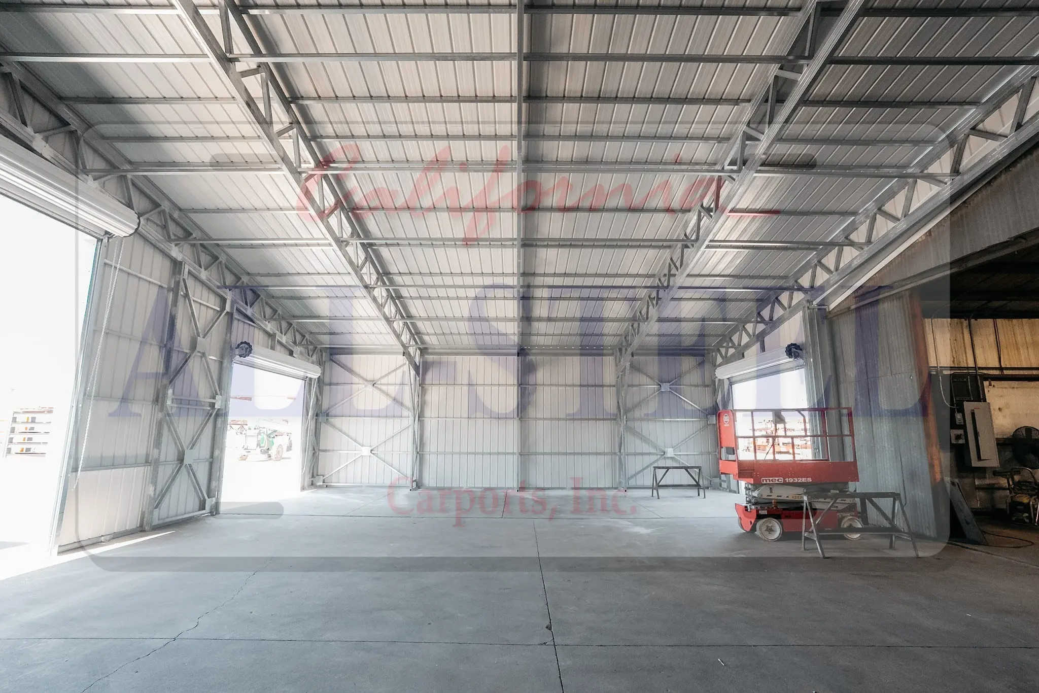 Exposed steel framing and a wide roll-up doorway inside a metal building